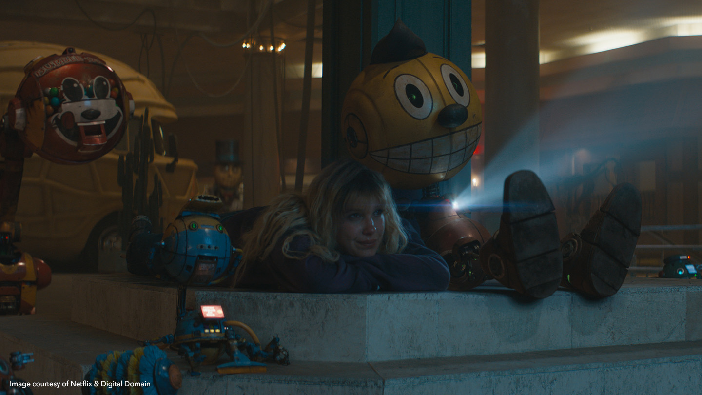 Millie Bobby Brown as Michelle Greene sitting with Cosmo in The Electric State